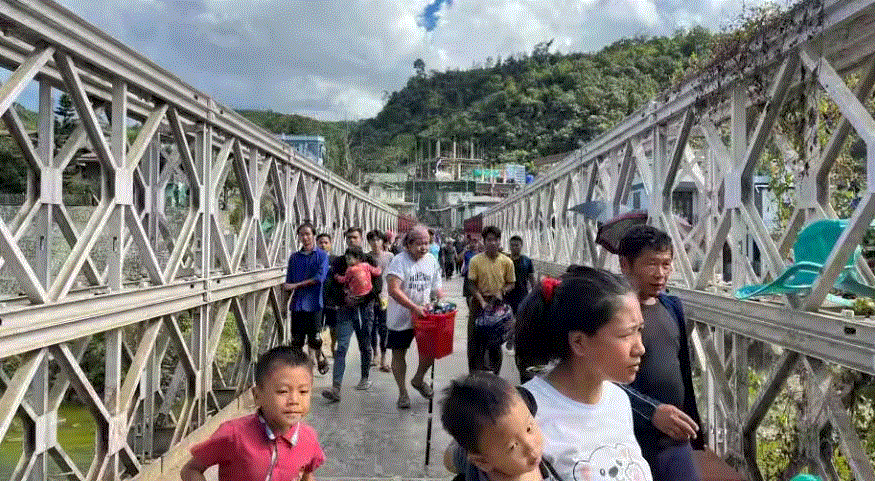 In this photograph from Nov 15, 2023, People who escaped Myanmar convey their possessions across a bridge that associates Myanmar and India at the boundary town of Zokhawthar, Champhai district, in India's northeastern province of Mizoram.